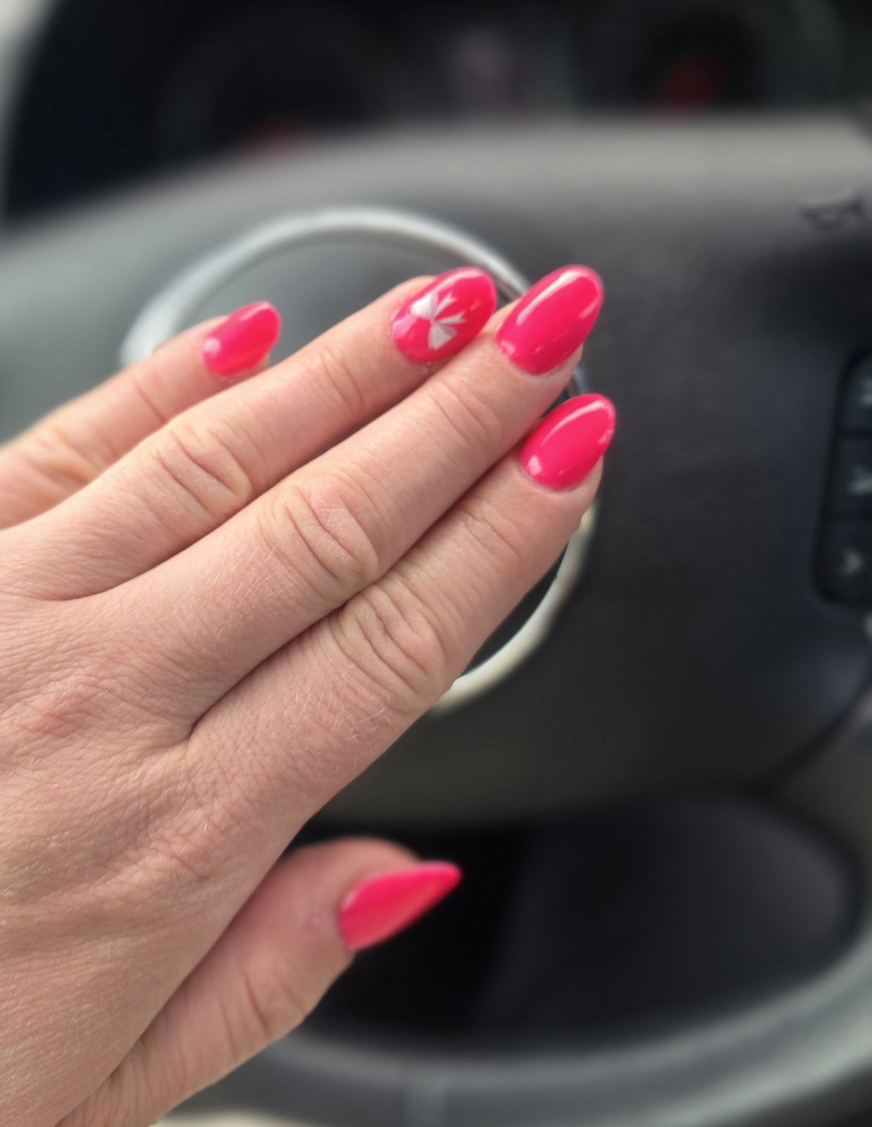 Korte roze nagels met witte bloemetjes, hand op een stuur