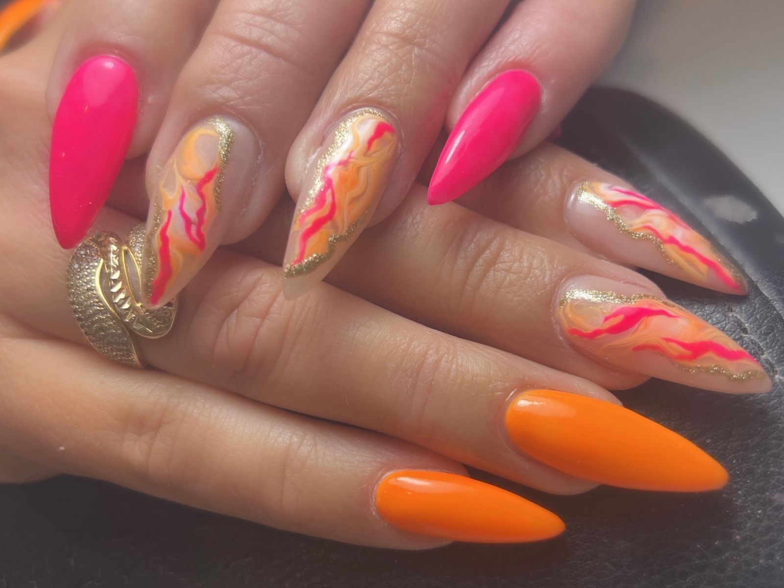 Lange amandelnagels in fel roze en oranje, met nude nagels met roze-oranje vlammen en bladgoud